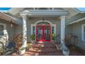 Charming entrance featuring vibrant red double doors, white columns, brick steps, and decorative plants at 1249 S Basin Ln, Sarasota, FL 34242