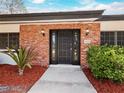 Brick front entry with a black wood door and landscape at 3825 Sarasota Golf Club Blvd, Sarasota, FL 34240