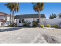 Front view of a single-story home with a green tiled roof and tropical landscaping at 519 South Dr, Anna Maria, FL 34216