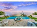 Stunning pool and patio area overlooking the water with built-in fire pit at 641 Key Royale Dr, Holmes Beach, FL 34217