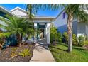 Front entry with walkway, tropical landscaping, and blue exterior at 3632 Shimmering Oaks Dr, Parrish, FL 34219