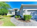 House exterior featuring a gray facade, landscaped walkway, and lush greenery at 9750 53Rd E Dr, Bradenton, FL 34211