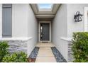 Front entry with gray door, stone accents, and landscape at 12689 Promenade Estates Blvd, Sarasota, FL 34238