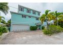 Three-story light blue home with three-car garage at 796 Jacaranda Rd, Anna Maria, FL 34216