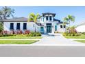 Modern home with white and gray exterior, palm trees, and paver driveway at 991 Seascape Pl, Sarasota, FL 34240