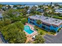 Aerial view of a condo building with a pool and parking area, surrounded by lush landscaping at 4307 Gulf Dr # 103, Holmes Beach, FL 34217