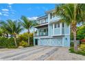 Two-story light blue house with a garage and tropical landscaping at 106 7Th S St, Bradenton Beach, FL 34217