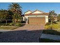 One-story house with brown garage door, brick driveway and well-manicured landscaping at 20680 Vita Ct, Venice, FL 34293