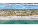 Stunning aerial view of a beachfront condo complex on a white sand beach with turquoise water and a blue sky at 420 Beach Rd # 203, Sarasota, FL 34242