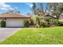 Spanish style home with tile roof, lush landscaping, and a two-car garage at 5575 Golf Pointe Dr, Sarasota, FL 34243