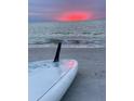 Paddleboard rests on the sandy beach as the sun sets over the ocean at 745 Bruce Ave, Clearwater Beach, FL 33767