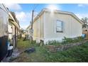 Side view of a tan mobile home, showing a small window and overgrown yard at 5829 Coventry Dr, Tampa, FL 33615