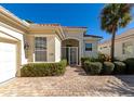 Front view of charming house with white walls, paver driveway, and manicured landscaping at 7156 Rue De Palisades # 3, Sarasota, FL 34238