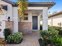 Front entry with dark gray door, stone accents, and landscaping at 153 Soliera St, Nokomis, FL 34275