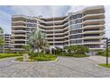 Modern high-rise condominium building with lush landscaping and paver driveway at 545 Sanctuary Dr # B406, Longboat Key, FL 34228