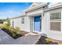 Stylish home exterior with blue front door, clean white walls, and well-kept landscaping at 8061 Moonbeam Ave, Sarasota, FL 34241