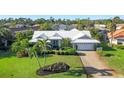 An aerial view showcasing the home's white tiled roof, surrounded by a well-maintained lawn and neighboring properties at 348 Red Ash Cir, Englewood, FL 34223