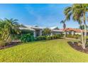 Exterior view of home with lush green landscaping, palm trees, and a white tiled roof at 348 Red Ash Cir, Englewood, FL 34223