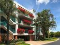 Condo building featuring colorful flower boxes on the balcony with lush landscaping and palm trees at 350 Gulf Of Mexico Dr # 211, Longboat Key, FL 34228