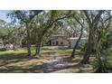 Tan house with covered patio, surrounded by lush trees at 6919 64Th E Ave, Palmetto, FL 34221