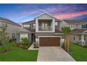 Two-story home with attached garage, balcony, manicured lawn, and beautiful landscaping at dusk at 33443 Landsman Loop, Wesley Chapel, FL 33543