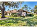 Exterior view of a single-story home with a tile roof, attached garage, and large lawn at 5561 Golf Pointe Dr, Sarasota, FL 34243