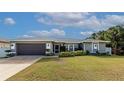 Well-maintained single-Gathering home with a two-car garage, manicured lawn, and vibrant landscaping at 6261 Keating Ave, North Port, FL 34291