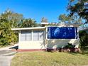 Tan mobile home with blue window awnings and tropical landscaping at 103 Oakwood Blvd, Sarasota, FL 34237