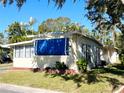 Side view of a tan mobile home with blue accents and landscaping at 103 Oakwood Blvd, Sarasota, FL 34237