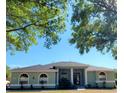 Single-story house with a light green exterior, columns, and lush landscaping at 13634 7Th Avenue Ne Cir, Bradenton, FL 34212