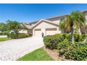Townhome exterior with a paved driveway, lush landscaping, and attached garage at 1720 Starling Dr # 103, Sarasota, FL 34231