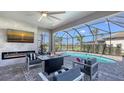 Relaxing outdoor living space with a fire pit, television, and views of the pool and landscaped backyard at 17744 Savory Mist Cir, Bradenton, FL 34211