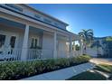 Side view of home with front porch, white pillars and railings, and neatly trimmed hedges at 1775 Stapleton St, Sarasota, FL 34239