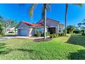 Tan house with red tile roof, palm trees, and a well-manicured lawn at 5833 Fairwoods Cir, Sarasota, FL 34243