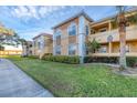 Front exterior view of a two-story condo building with lush landscaping and palm trees at 1130 Villagio Cir # 203, Sarasota, FL 34237