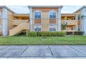 Front view of a two-story condo building with stairs leading to the entrance, green lawn, and sidewalk at 1130 Villagio Cir # 203, Sarasota, FL 34237