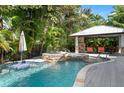 A lush backyard pool with a built-in spa and outdoor kitchen area at 116 50Th St, Holmes Beach, FL 34217