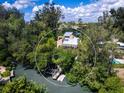 Aerial view of a canal-front property surrounded by dense foliage and lush greenery with personal boat dock at 1214 Sea Plume Way, Sarasota, FL 34242