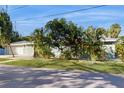 Single-story home with a paved driveway, attached two-car garage, and tropical landscaping at 1220 26Th W St, Bradenton, FL 34205