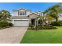 Two-story house with stone accents and teal shutters, a paved driveway, and lush landscaping at 3409 Anchor Bay Trl, Bradenton, FL 34211