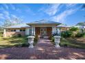 Inviting brick home with a paved walkway, manicured lawn, and ornamental urns at the entrance at 7945 Palmer Blvd, Sarasota, FL 34240