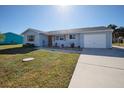 Newly painted light blue home with a landscaped lawn and a two-car garage at 18647 Kerrville Cir, Port Charlotte, FL 33948