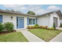 Updated home featuring a stylish front entry with a blue door and landscaping at 8103 San Bernardino Dr, Port Richey, FL 34668