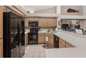 Well-lit kitchen features black appliances, wood cabinets, and white tile floors at 9443 Burnam Dr, Weeki Wachee, FL 34613