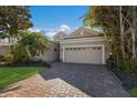 Tan house with a three-car garage and a brick driveway at 3614 Summerwind Cir, Bradenton, FL 34209