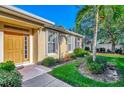 Inviting front yard with a walkway leading to the golden front door, lush landscaping, and palm trees at 2520 Terracina Dr, Venice, FL 34292