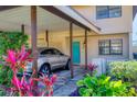 Stylish home with a covered carport featuring a vibrant blue front door and beautiful, colorful landscaping at 3468 51St Avenue W Dr, Bradenton, FL 34210