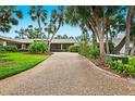 Long gravel driveway leading to a house with tropical landscaping at 5345 Siesta Ct, Sarasota, FL 34242