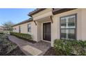 Front walkway and entrance of a house with a dark wood door, side window, and green shrubs at 5737 Semolino St, Nokomis, FL 34275