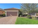 Front exterior of a house with a two-car garage, brown tile roof, and landscaped yard at 5737 Semolino St, Nokomis, FL 34275